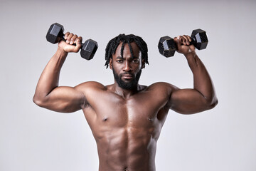 Fototapeta na wymiar very strong young guy bodybuilder of african appearance doing exercises with dumbbells isolated on white background. Fitness athlete male with muscular body, raising arms up. Sports and fitness.