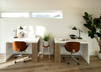 Small contemporary home office with two small desks, rolling chairs, and lots of light