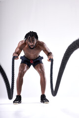 Attractive muscular african man working out with heavy ropes isolated over white studio background. Photo of handsome man with naked torso durign workout. sport, fitness concept. portrait