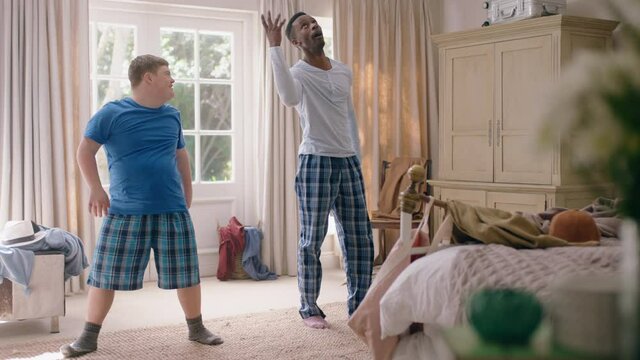 happy father dancing with teenage son having fun enjoying playful dance enjoying weekend at home wearing pajamas