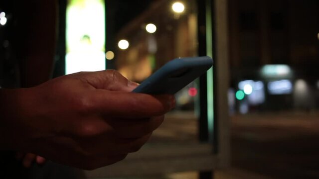 Young african man looking at cellphone device at night in city sidewalk