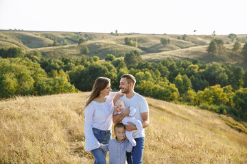 family in light outfits with small children posing against the backdrop of nature