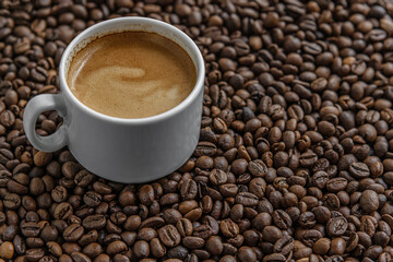 aromatic freshly brewed coffee in a white porcelain cup among coffee beans