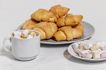 cup of coffee, marshmallows and sweet homemade shortcrust pastry bagels on white glossy surface