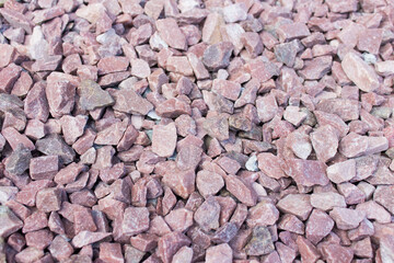 Many small decorative stones used in landscape design with pink color tint.