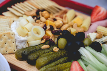 Closeup of a table with pickles, celery, strawberries, olives, cheese, hearts of palm, cookies, nuts and ham