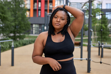 Portrait of confident afro american woman in black tracksuit posing at camera, have rest, black fat...