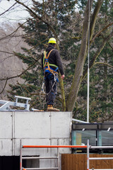 Man with a harness on the roof of a building.