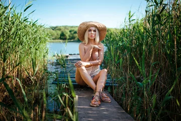 Beautiful model girl posing on the field enjoying nature outdoors in a straw hat. Beauty blond young woman with long straight blond hair close up portrait © руслан малыш
