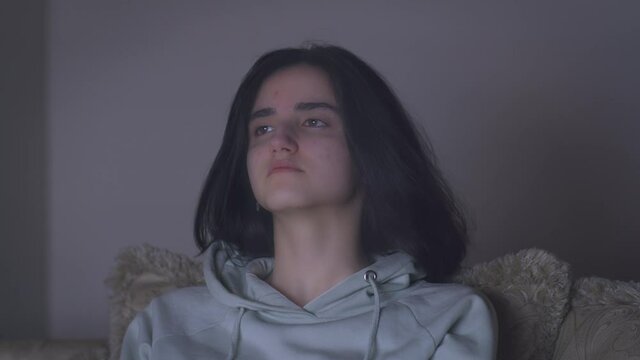 Portrait of a girl with black hair watching tv late at night alone