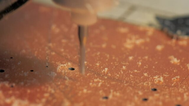 A small CNC drilling machine makes holes in the future motherboard. Printer device Circuit board. Manufacture of electronic components. Inside a modern facility. Close up.
