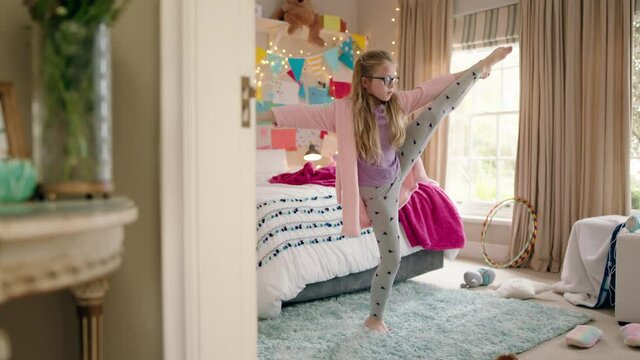 happy little girl dancing in bedroom practicing ballet dance moves having fun playing pretend wearing pajamas enjoying weekend at home