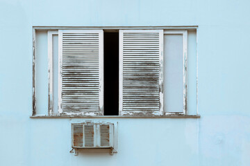 window in painted wood deteriorated due to weather on a building facade