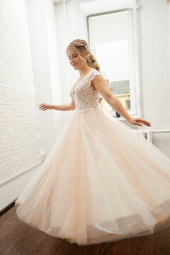 Beautiful bride with a lush hairstyle in a pink dress indoors