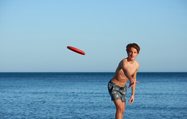 A portrait of a young fit caucasian male playing frisbee in the beach