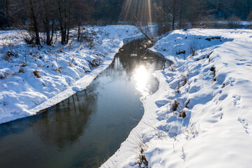 Drone shot flying on forest and river in winter.