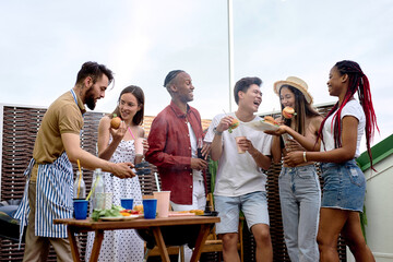 happy diverse friends having fun at barbecue party outdoor in backyard. Young cheerful people doing bbq dinner, eacting burgers, drinking lemonade. Youth lifestyle, food and friendship concept