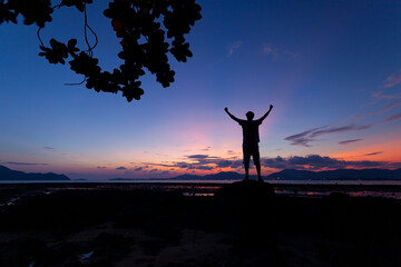 Fototapeta na wymiar Silhouette of man raised his hands with tree frame at sunset or sunrise sky