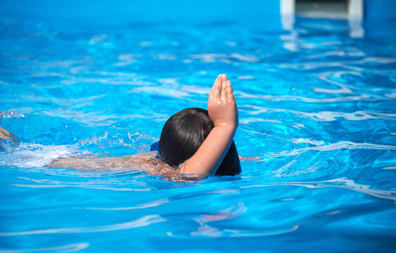 boy diving in pool makes shark sign with his hand on his head