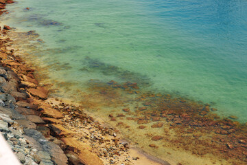 Close up of stones and clear water on the shore of a beach