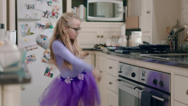 happy ballerina girl dancing in kitchen wearing purple tutu having fun performing funny dance moves enjoying weekend celebration at home