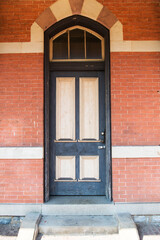 black door with an ornament in a brick wall