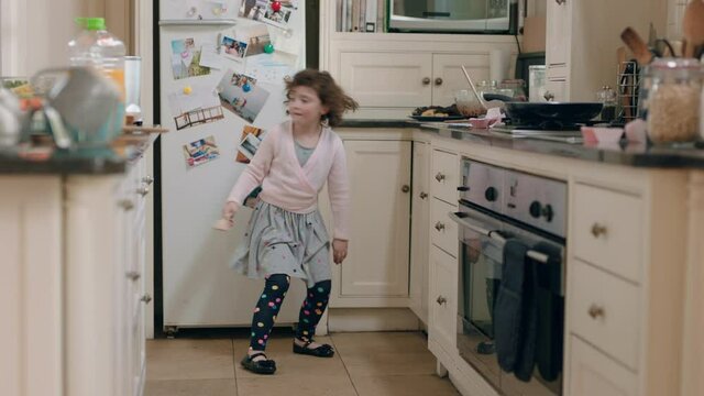 happy little girl dancing in kitchen having fun doing funny dance moves enjoying weekend at home