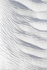 Textured effect of waves on surface of gray-white stone. Pamukkale travertine surface in Turkey.