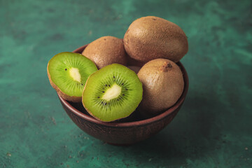 Bowl with fresh kiwi fruit on color background