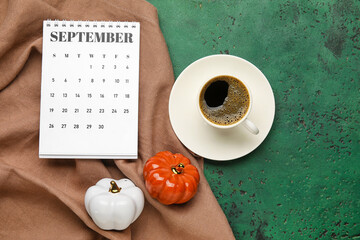 Calendar with cup of coffee and pumpkins on color background