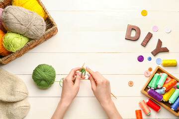 Word DIY and woman knitting on white wooden background