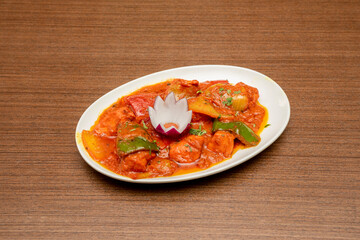 Indian recipe of chicken dopiaza with lots of onions in the sauce of the stew on a white tray