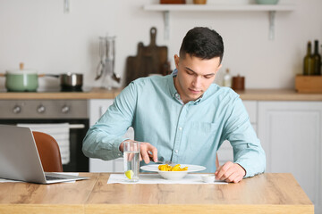 Fototapeta na wymiar Young man eating tasty ravioli at home