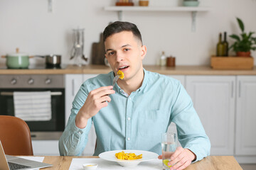 Fototapeta na wymiar Young man eating tasty ravioli at home
