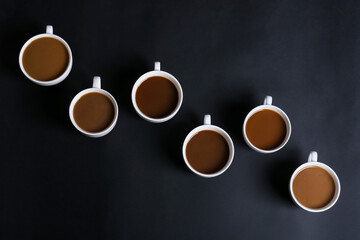 Cups of tasty coffee on dark background