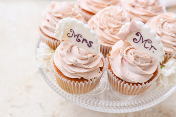 Dessert stand with tasty wedding cupcakes on light background