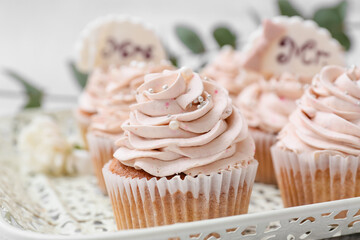 Tray with tasty wedding cupcakes on light background