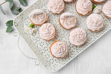 Obraz na płótnie Canvas Tray with tasty wedding cupcakes on light background