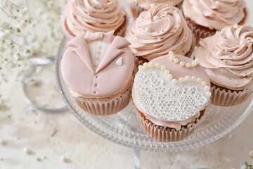 Dessert stand with tasty wedding cupcakes on light background