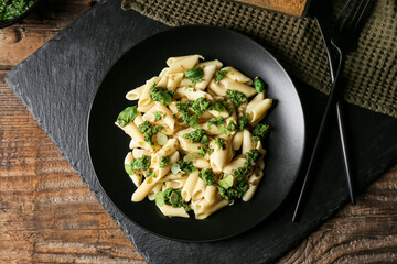 Plate with tasty pasta and pesto sauce on wooden background