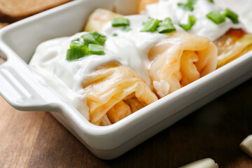 Baking dish with tasty stuffed cabbage rolls and sauce on table, closeup