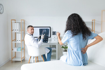 Naklejka premium Mature doctor showing x-ray scan to patient in clinic