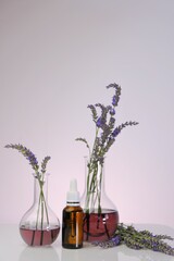 Lavender Essential oil.Glass bottle with a pipette, laboratory flasks with lavender flowers on a light purple background. natural cosmetics with lavender extract. 