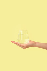 Female hand with glass of water on color background