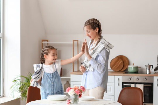 Little girl and her mother giving each other high-five in kitchen - Powered by Adobe