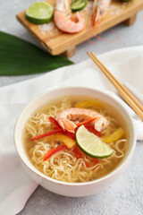 Bowl of tasty Thai soup with shrimps on grey background