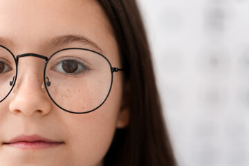 Little girl wearing new eyeglasses at ophthalmologist's office, closeup