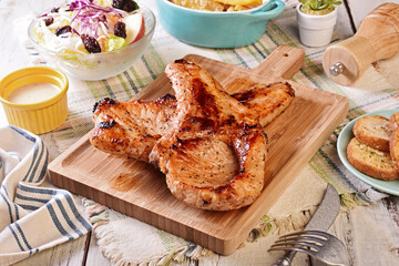 Two grilled tomahawk pork chops on wooden board 