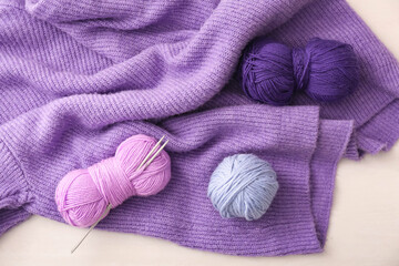 Yarn with knitting needles and sweater on white background