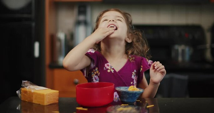 Toddler girl helping make macaroni and cheese.
